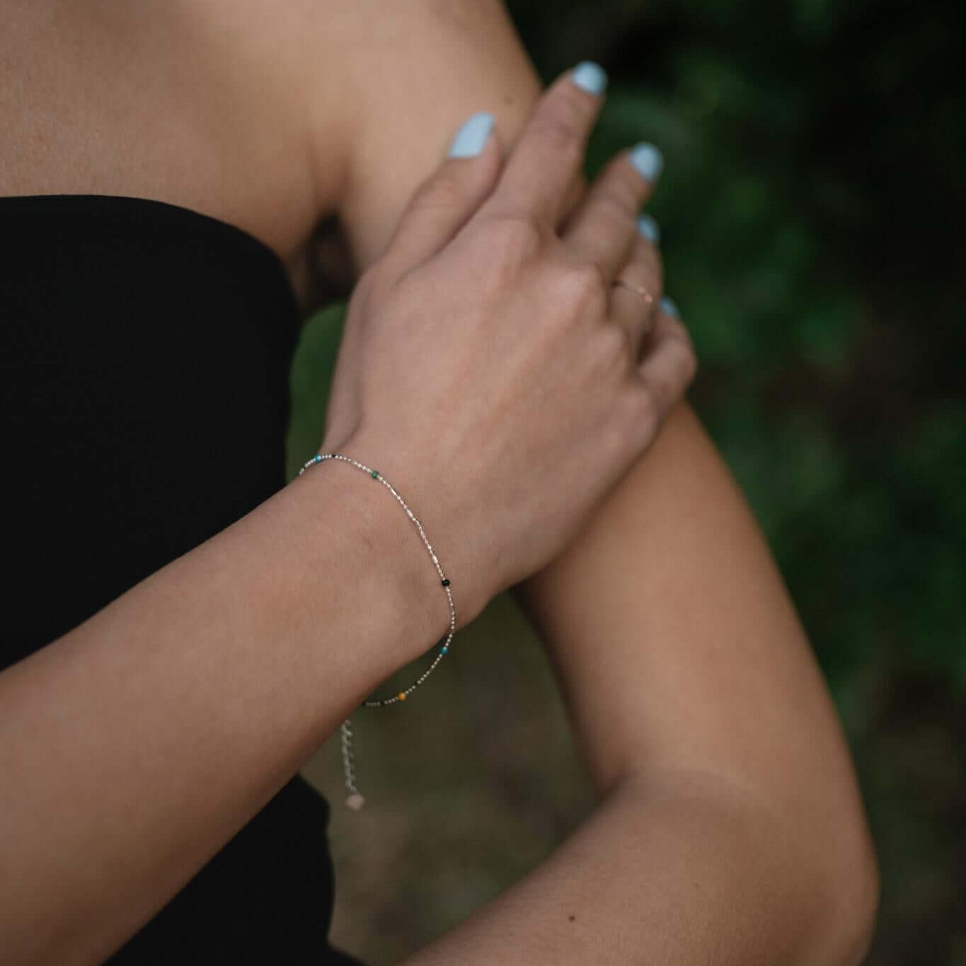 Сребърна многоцветна гривна S925, носена от жена на открито, акцентираща на елегантност и стил.