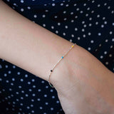 Сребърна гривна S925 с многоцветни елементи върху ръката на човек, носеща стилна дреха.