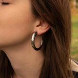 Обеци Класически Халки в 2 Цвята на жена с дълга коса, носеща черни халки от медицинска стомана.