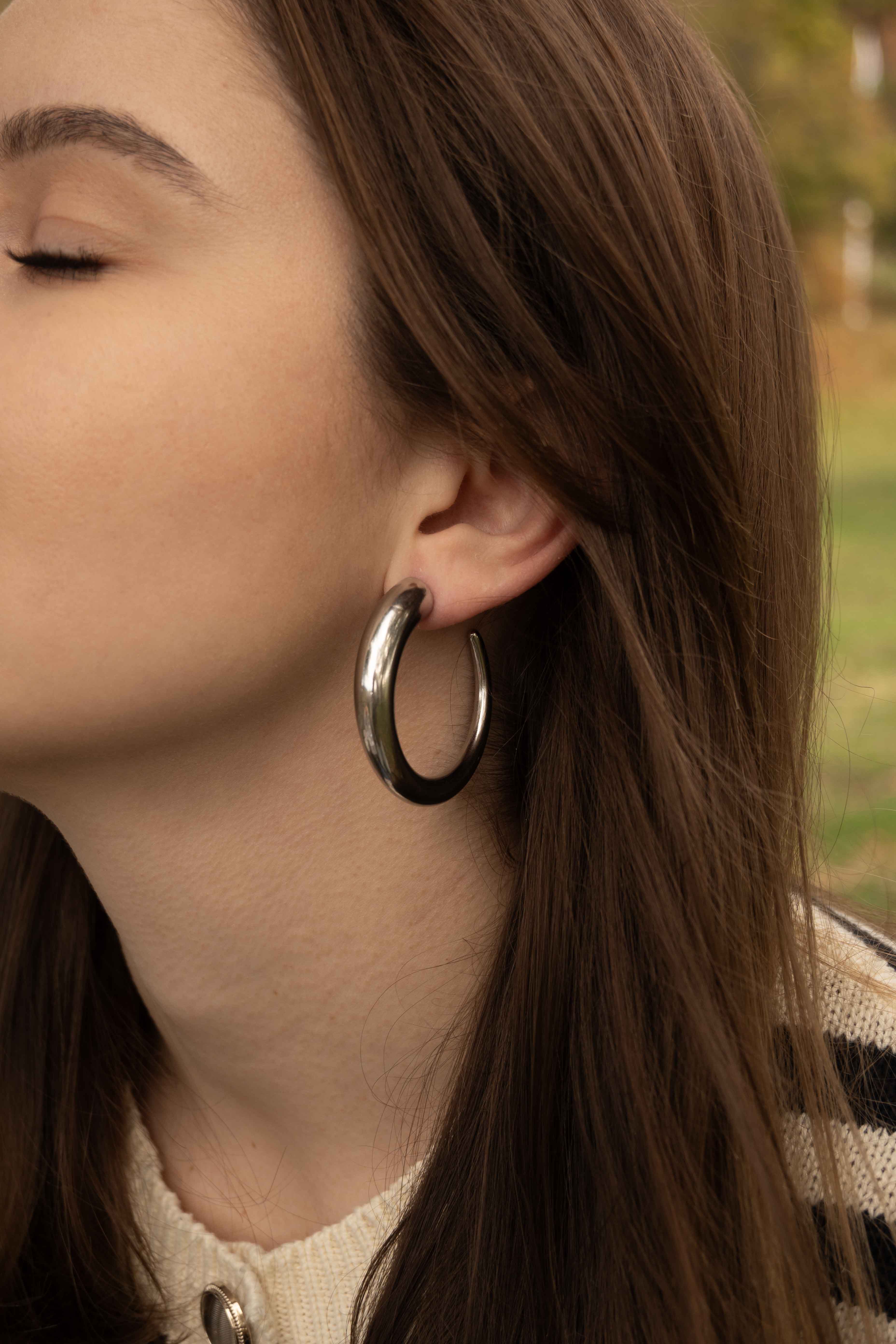 Обеци Класически Халки в 2 Цвята на жена с дълга коса, носеща черни халки от медицинска стомана.