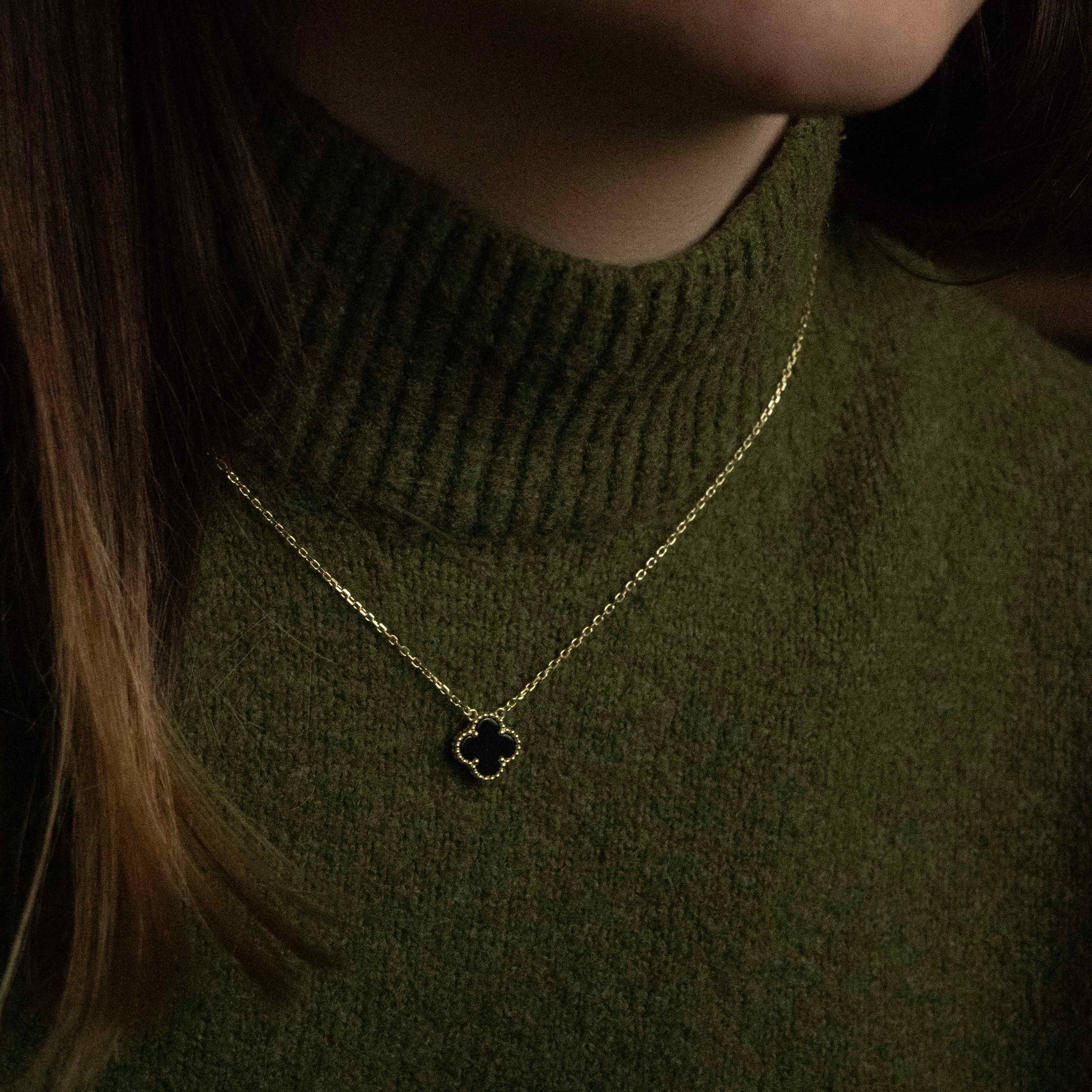 Колие One Clover от сребро с 14К златно покритие, носено от жена с зелена жилетка.