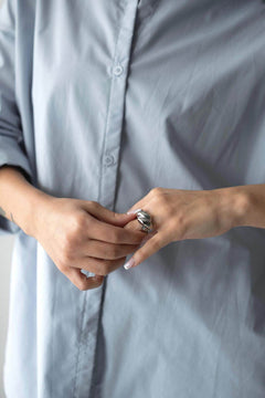 Woman wearing a chunky ring with 18K gold plating over a pale blue shirt, showcasing stylish jewelry.