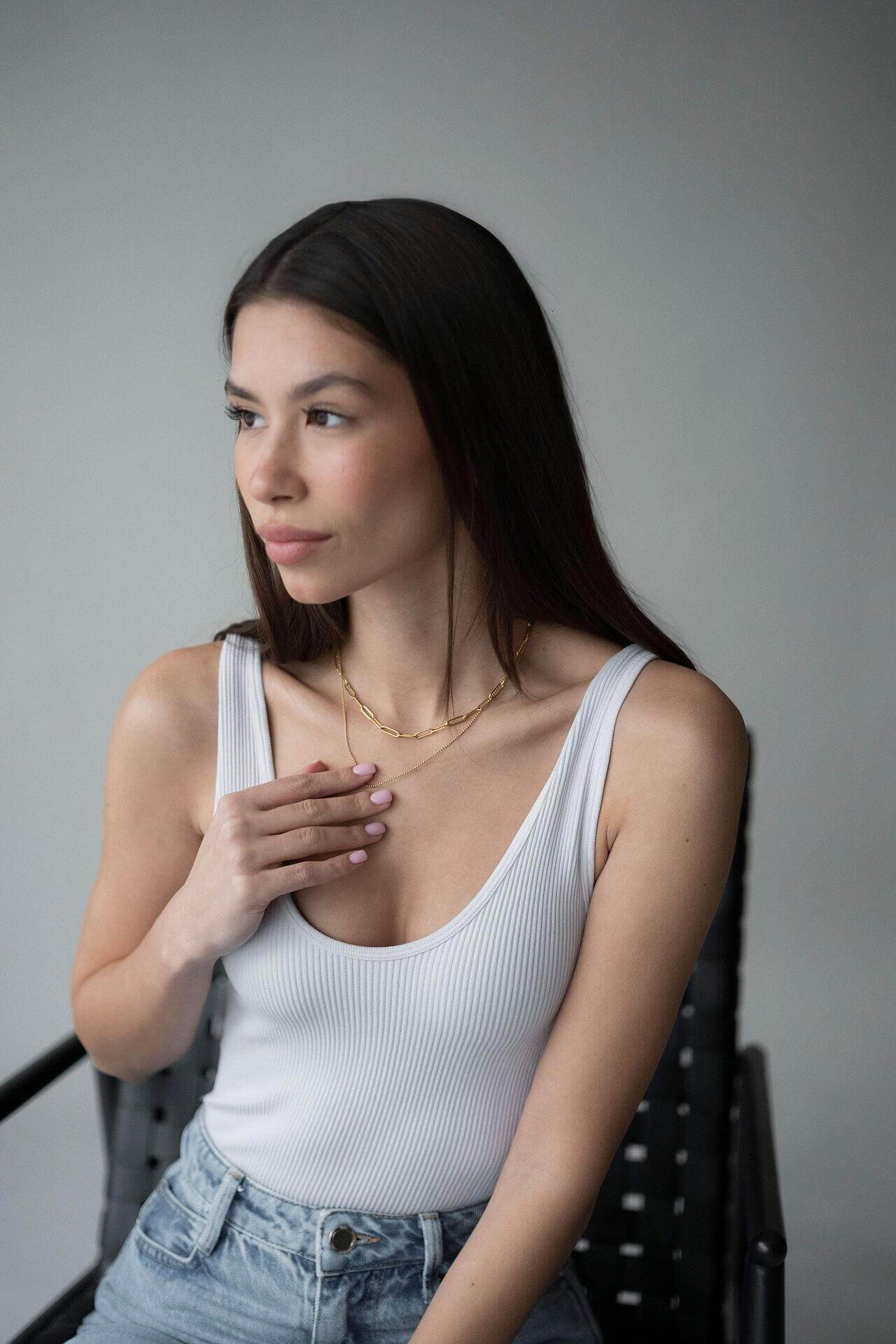 Woman wearing a double paperclip necklace and chain in gold, showcasing a stylish outfit with a modern aesthetic.