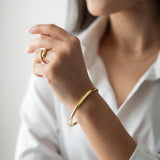 Woman wearing Ayra bracelet with 18K gold plating and stylish ring, showcasing elegant jewelry.
