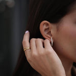 Жена с медна коса, носеща златист пръстен Liberta с 18К златно покритие и обеци.